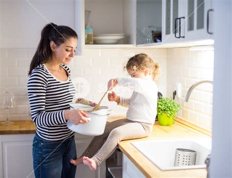 Beautiful Young Mother With Her Cute Little Daughter In The Kitchen Cooking Together Mixing