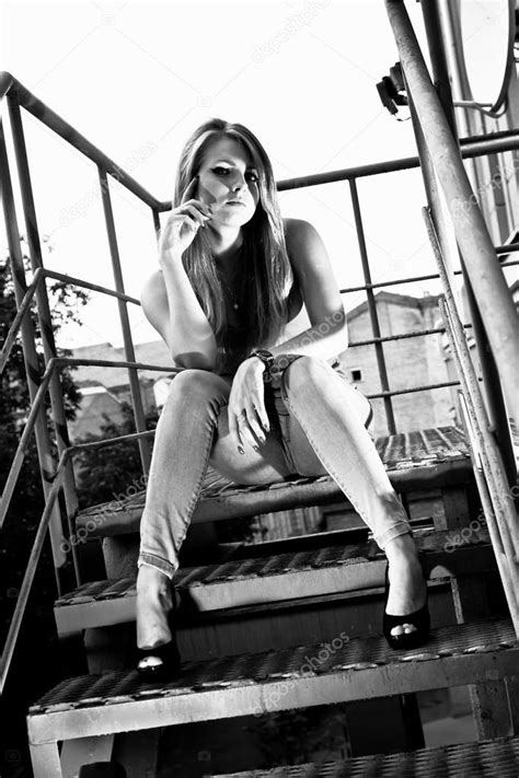 金属製の階段の一番上のステップの上に座ってジーンズでセクシーな女性 — ストック写真 © Kryzhov 37109867