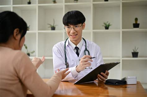 A Professional Asian Male Doctor Examining A Female Patient In The