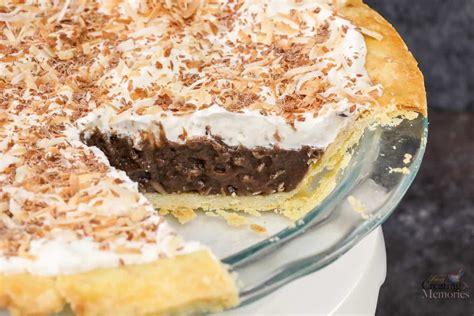 A Chocolate Pie With White Frosting And Toasted Coconut On Top Is Shown