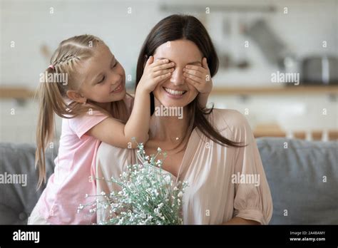Little Daughter Preparing Surprise For Smiling Mother Covering Her