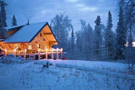 Log Cabin In The Woods Decorated With Christmas Lights At Twilight Near