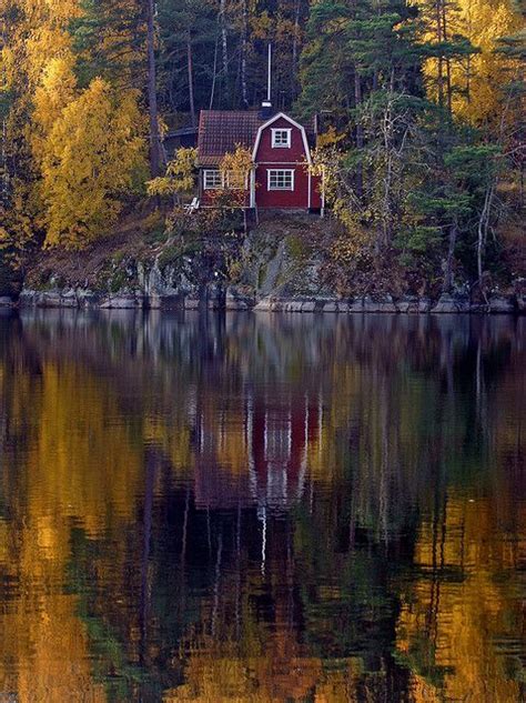 A Red House Sitting On Top Of A Lush Green Hillside Next To A Body Of Water
