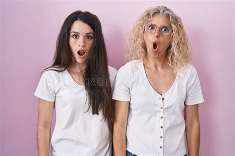 Mother And Daughter Standing Together Over Pink Background In Shock Face Looking Skeptical And