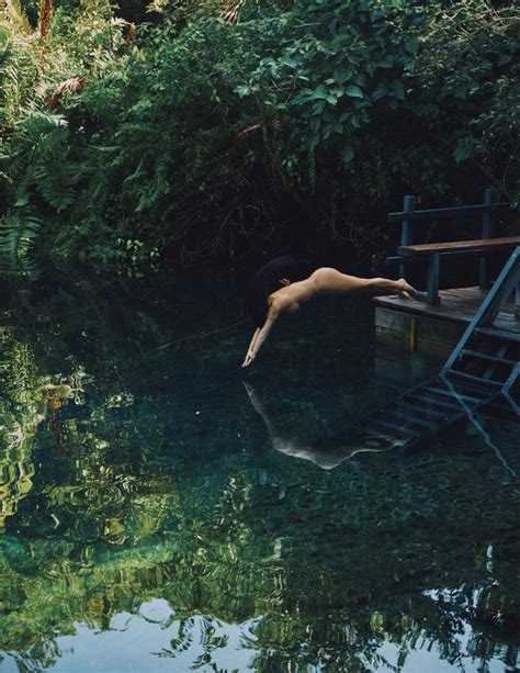 A Naked Woman Floating In Water Next To A Wooden Dock With Stairs Leading Up To It