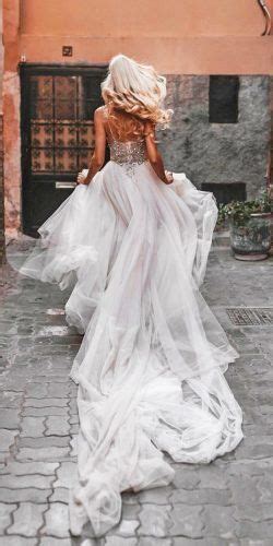A Woman In A Wedding Dress Walking Down The Street With Her Back To The Camera