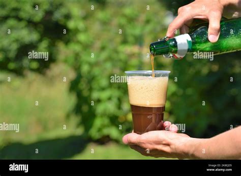 Hand Pouring Dark Beer Into A Plastic Glass Stock Photo Alamy