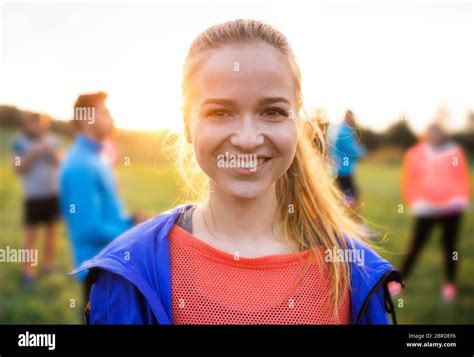 A Portrait Of Young Woman With Large Group Of People Doing Exercise In