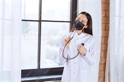 Free Photo Doctor In Black Mask With A Stethoscope Standing By The Window And Checking The