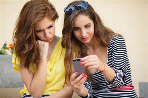Twee Meisjes Die Fotos Op Mobiele Telefoon Kijken Stock Afbeelding
