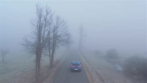 Car Driving Along The Scary Foggy Country Road Leading Through Misty