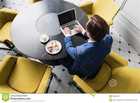Concentrated Male Worker Typing On Laptop During Breakfast Stock Photo