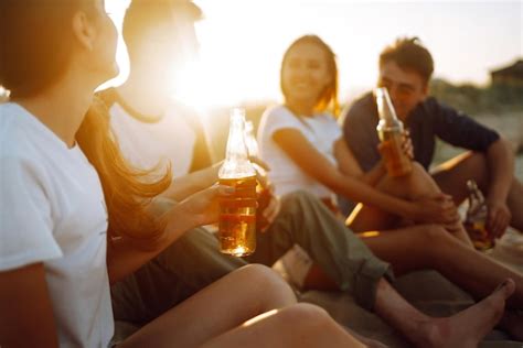 Premium Photo Young People Sitting Together At Beach Drinking Beer