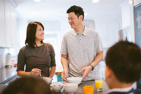 Husband And Wife Smile In Kitchen As They Serve Breakfast By Stocksy
