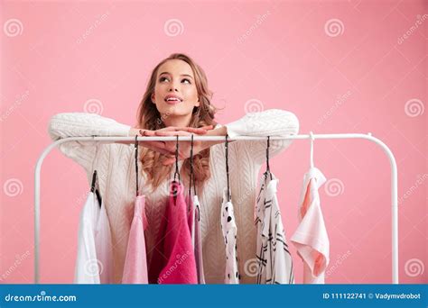 Pretty Lady Choosing Clothes Hanging On Rack In Workshop Stock Image