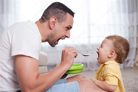 Handsome Young Man Is Feeding His Child Stock Photo By ©iakovenko123