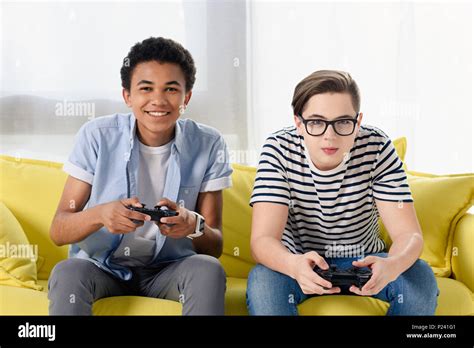 Happy Multicultural Teen Boys Playing Video Game At Home Stock Photo