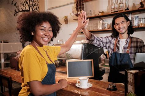 Two Baristas Team Hand In Hand And Cheerful Smile At Counter Bar Of Coffee Shop Stock Image