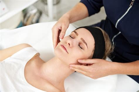 Premium Photo Close Up Of Doctor Cosmetologist Hands Massaging The Face Of Relaxed Young Woman