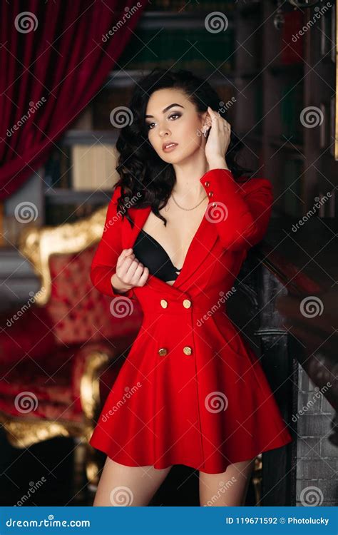 Muchacha Atractiva En El Vestido Rojo Undresiing Tocando Su Pecho Y