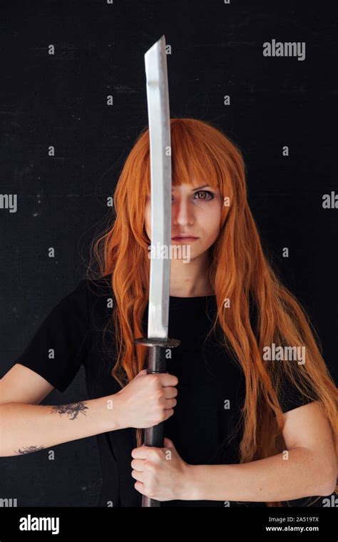 Woman Cosplayer Anime With Red Hair Holds A Japanese Sword Stock Photo