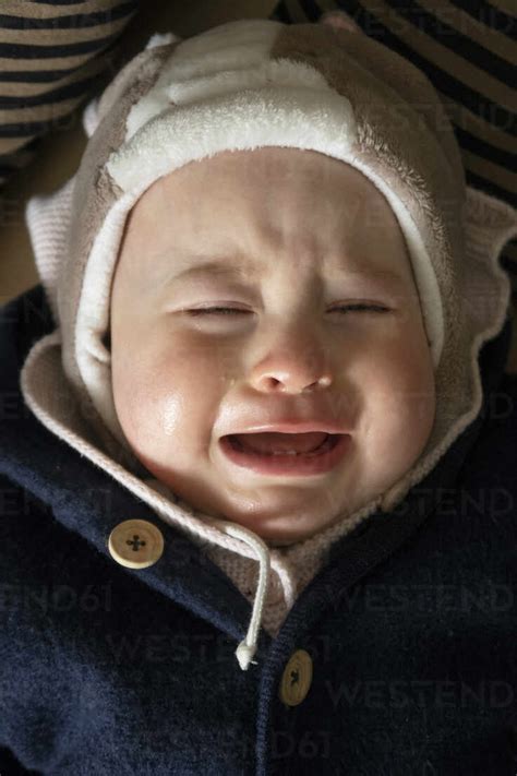 Baby Girl Crying While Lying Down In House Stock Photo