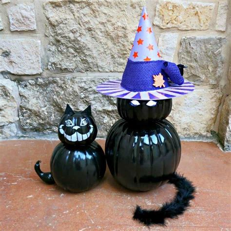 Two Black Pumpkins With Hats On Them Sitting Next To Each Other