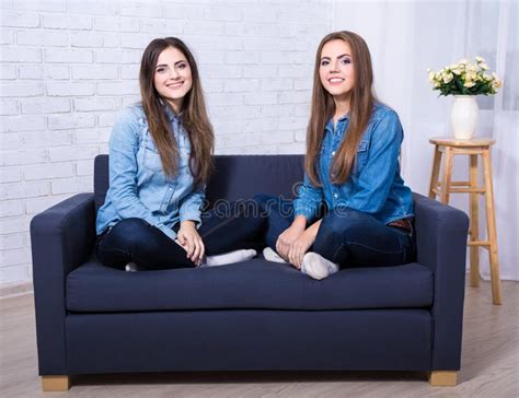 Portrait Of Two Young Women Sitting On Sofa In Living Room Stock Image