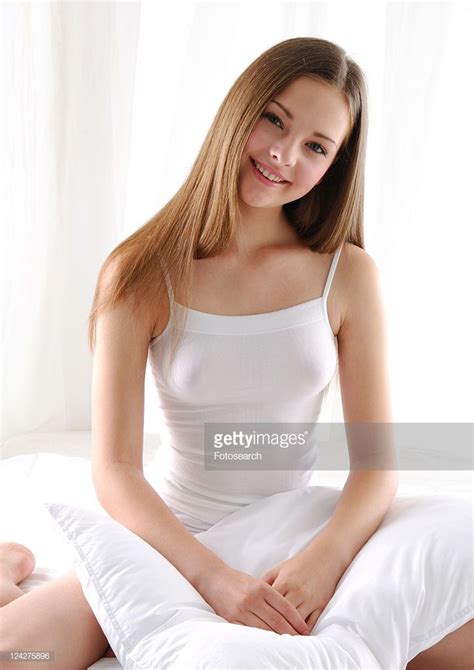 Portrait Of A Young Woman Kneeling On The Bed With A Pillow And
