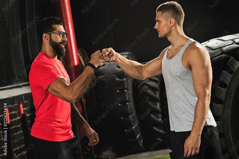 Two Muscular Men Are Making Fist Bump Gesture During Workout In The Gym