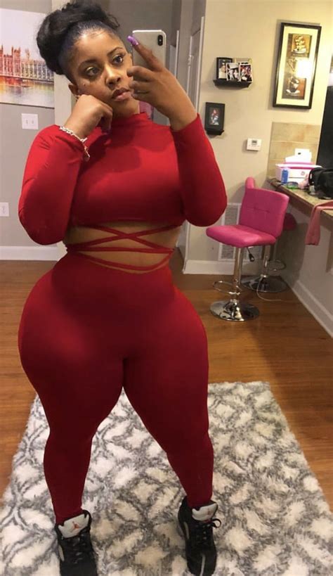A Woman In A Red Outfit Taking A Selfie While Standing On A White Rug