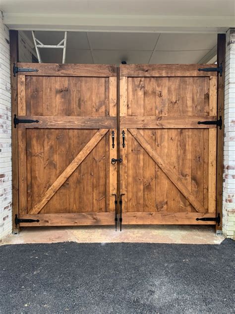 Two Wooden Garage Doors Are Open In Front Of A Brick Wall And White
