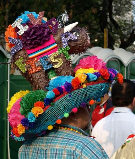 A Man Wearing A Colorful Hat With Flowers On Its Head And Other People