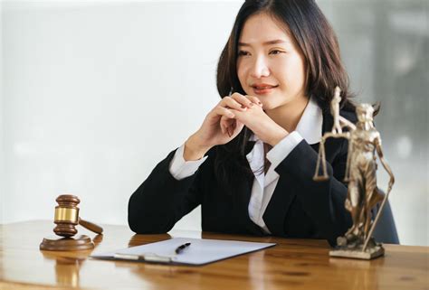 Serious Female Asian Lawyer With Smiling Sitting At Workplace And