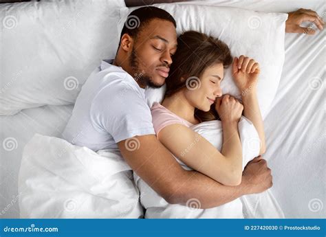 Top View Of Loving Interracial Couple Sleeping In Bed Hugging Each
