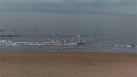 Aerial Top View Beautiful Young Blonde Woman Walking Along The Sea On A Beach Nymph In White