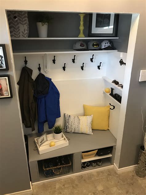 A Coat Rack With Two Coats Hanging On It And Some Yellow Pillows In The