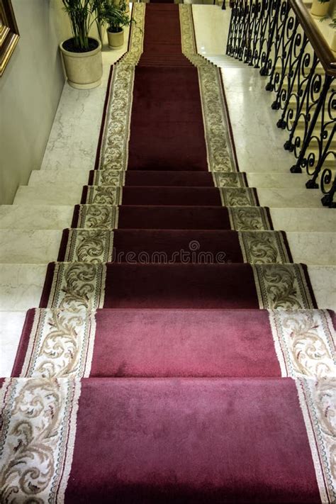 Red Carpet Leading Up Stone Staircase With Vaulted Ceiling Stock Photo