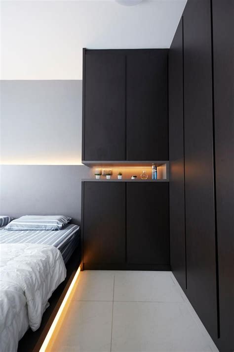 A Bed Sitting Under A Light In A Bedroom Next To A Wall Mounted Cabinet