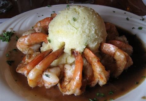 A White Plate Topped With Meat And Shrimp Covered In Gravy On Top Of