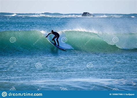 Surfer On Blue And Green Ocean Wave Riding A Surfboard Stock Photo