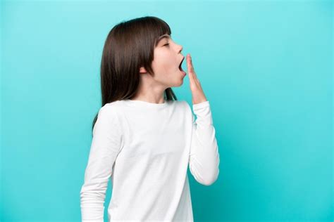 Premium Photo Little Caucasian Girl Isolated On Blue Background Yawning And Covering Wide Open