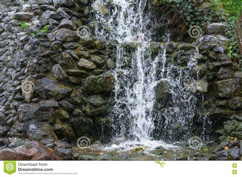 Small Waterfall Cascade Flowing Over Mossy Boulders Stock Photo