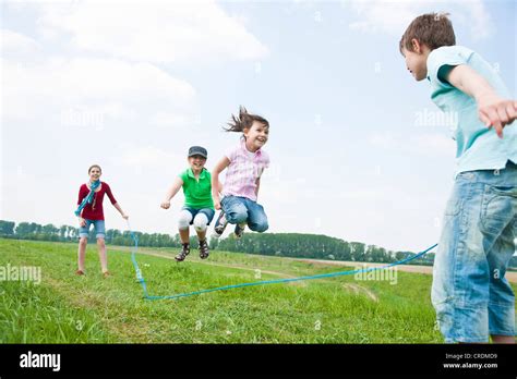 Four Friends Three Girls And A Babe Jumping Ropes In A Meadow Stock Photo Alamy