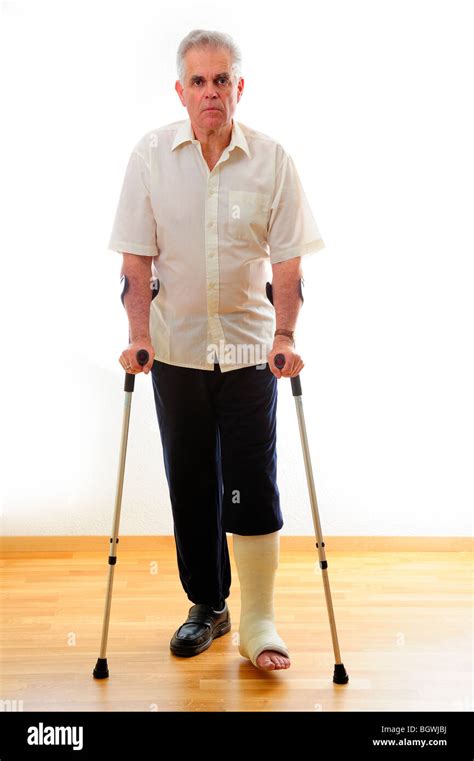 A Man With A Broken Leg On Crutches Against A White