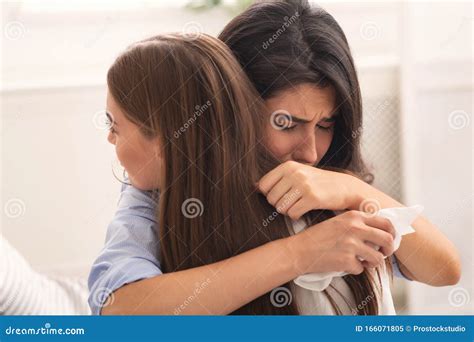 Girl Crying Hugging Her Compassionate Friend Sitting On Couch Indoor