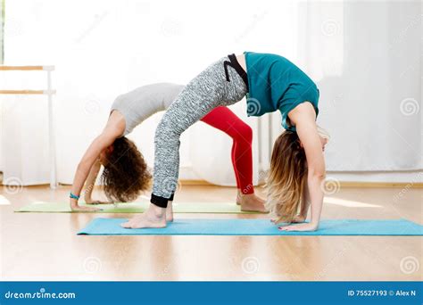 Flexible Young Women Practice Chakrasana Asana In Yoga Studio Stock