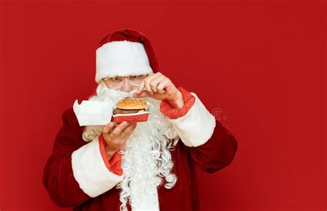 Astonished Santa Claus Stands On A Red Background With A Burger In His