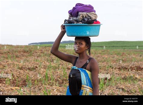 A Young African Woman Carrying A Wash Basin Full Of Laundry On Her Head