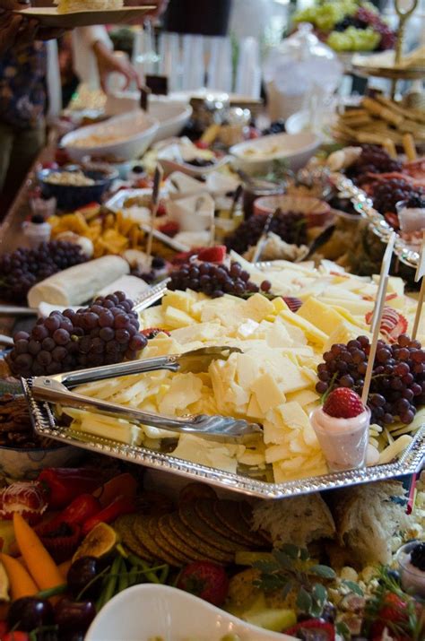 a buffet table filled with lots of different types of cheeses and fruit